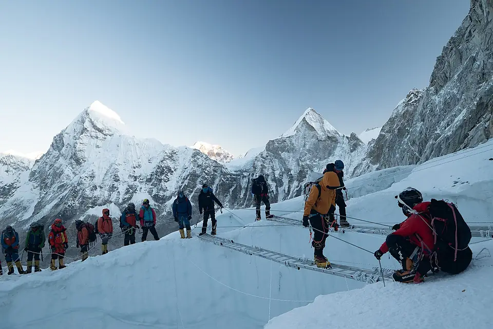 Climbers crossing ladders in the Khumbu Icefall